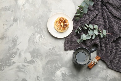 Flat lay composition with hot drink and warm plaid on grey table, space for text