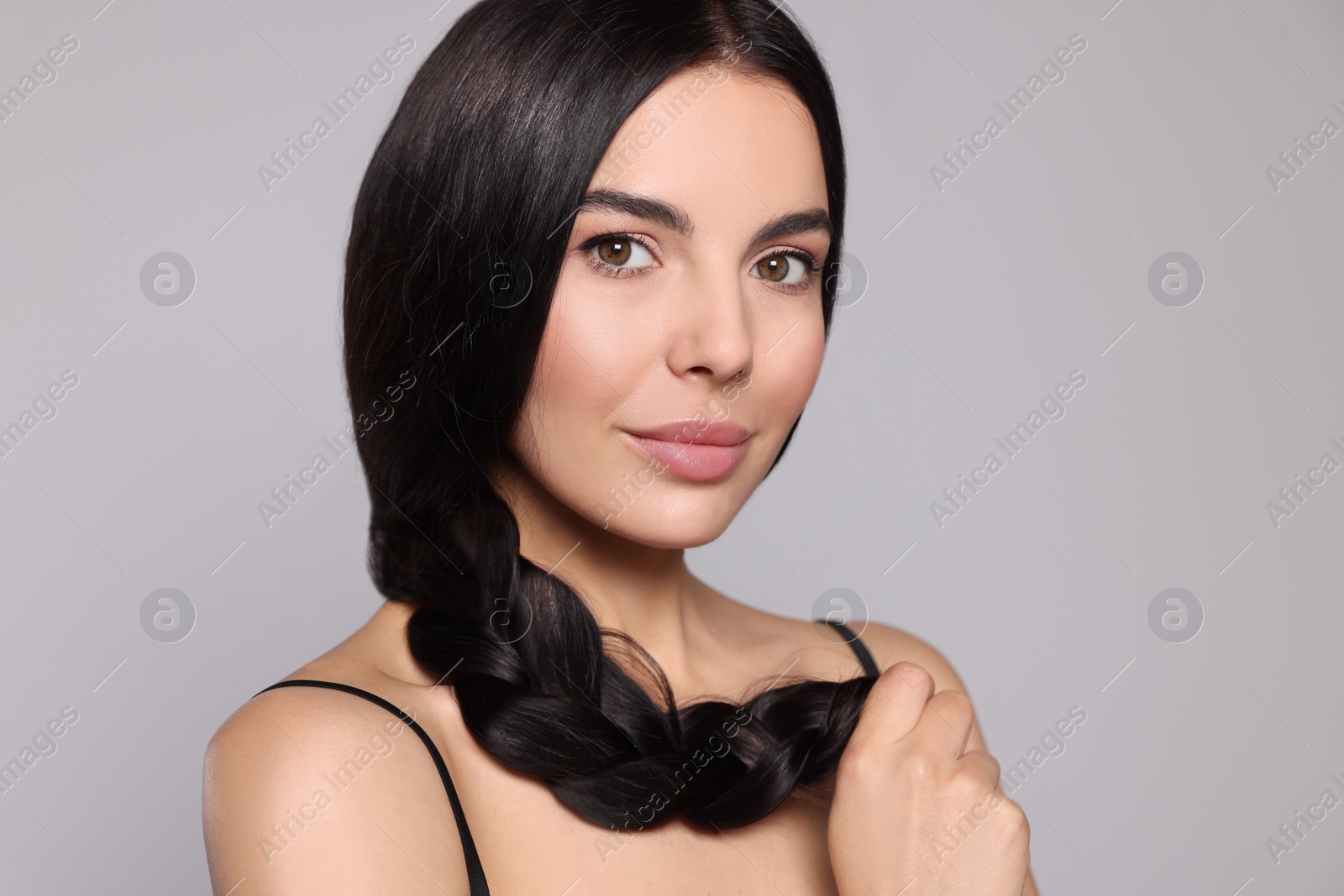 Photo of Portrait of beautiful young woman with healthy strong hair on light grey background