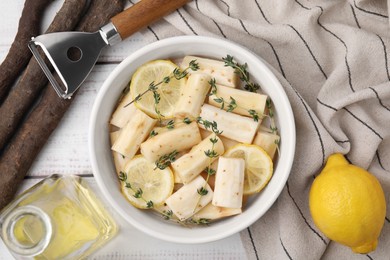 Photo of Dish with raw salsify roots, lemon and thyme on white wooden table, flat lay