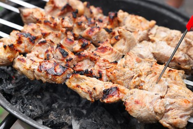 Photo of Measuring temperature of delicious kebab on metal brazier, closeup