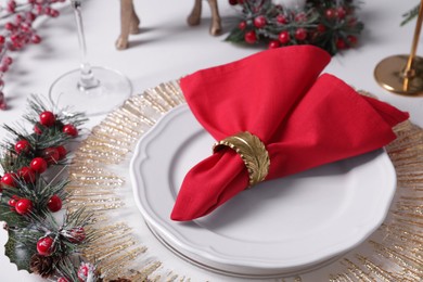 Photo of Plates with red fabric napkin and festive decor on white table