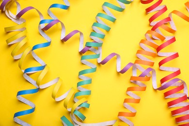 Photo of Rainbow serpentine streamers on yellow background, flat lay. LGBT pride