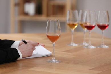 Photo of Sommelier making notes during wine tasting at table indoors, closeup
