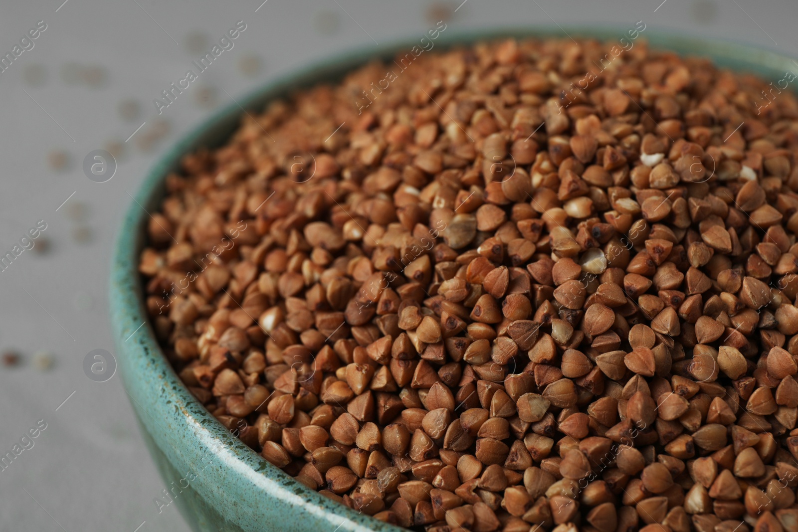 Photo of Uncooked buckwheat in bowl on table, closeup