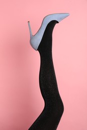 Photo of Woman wearing black tights and high heel shoe on pink background, closeup