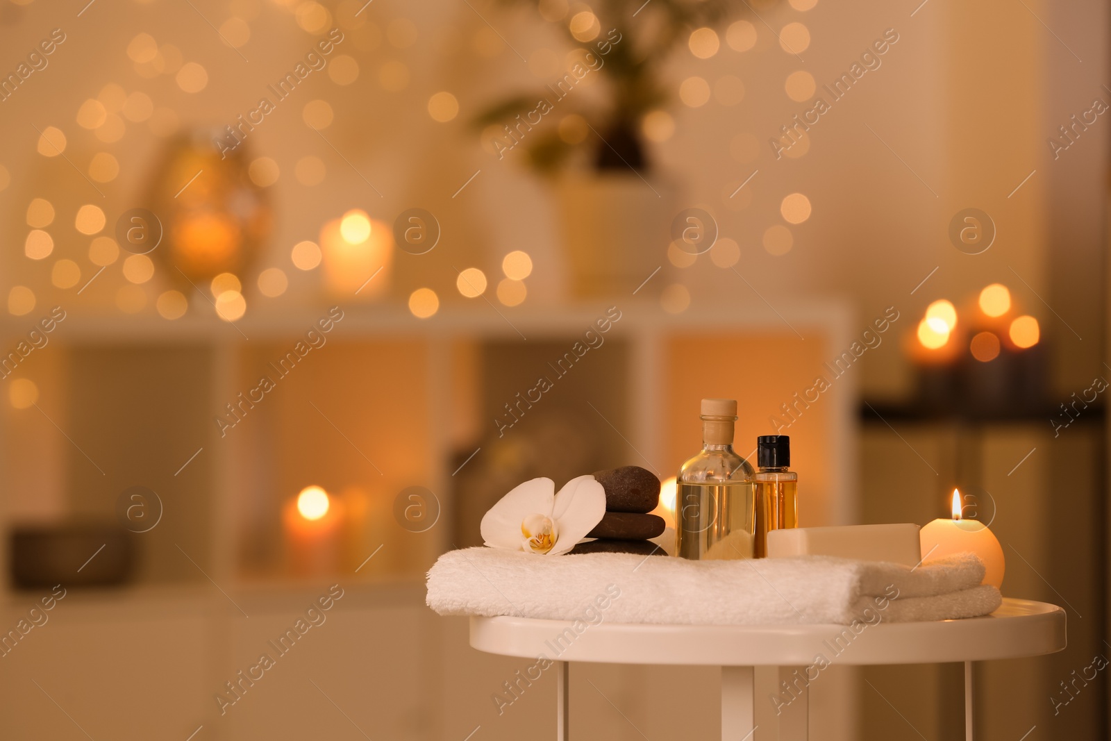 Photo of Spa supplies, burning candle and flower on table in beauty salon, space for text