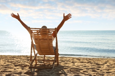 Man relaxing on deck chair at sandy beach. Summer vacation