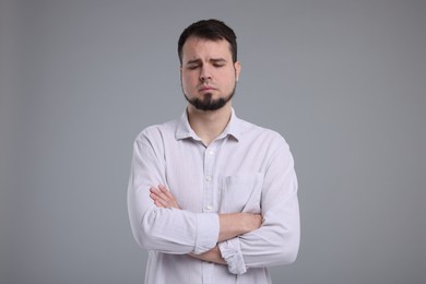 Photo of Portrait of sad man with crossed arms on grey background