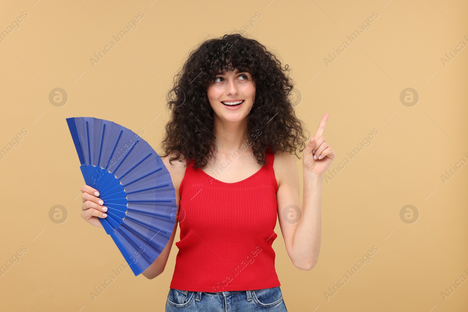 Photo of Happy woman holding hand fan on beige background