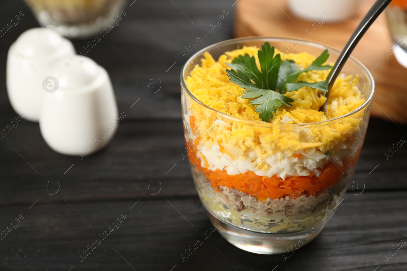 Photo of Traditional russian salad Mimosa served on dark wooden table. Space for text