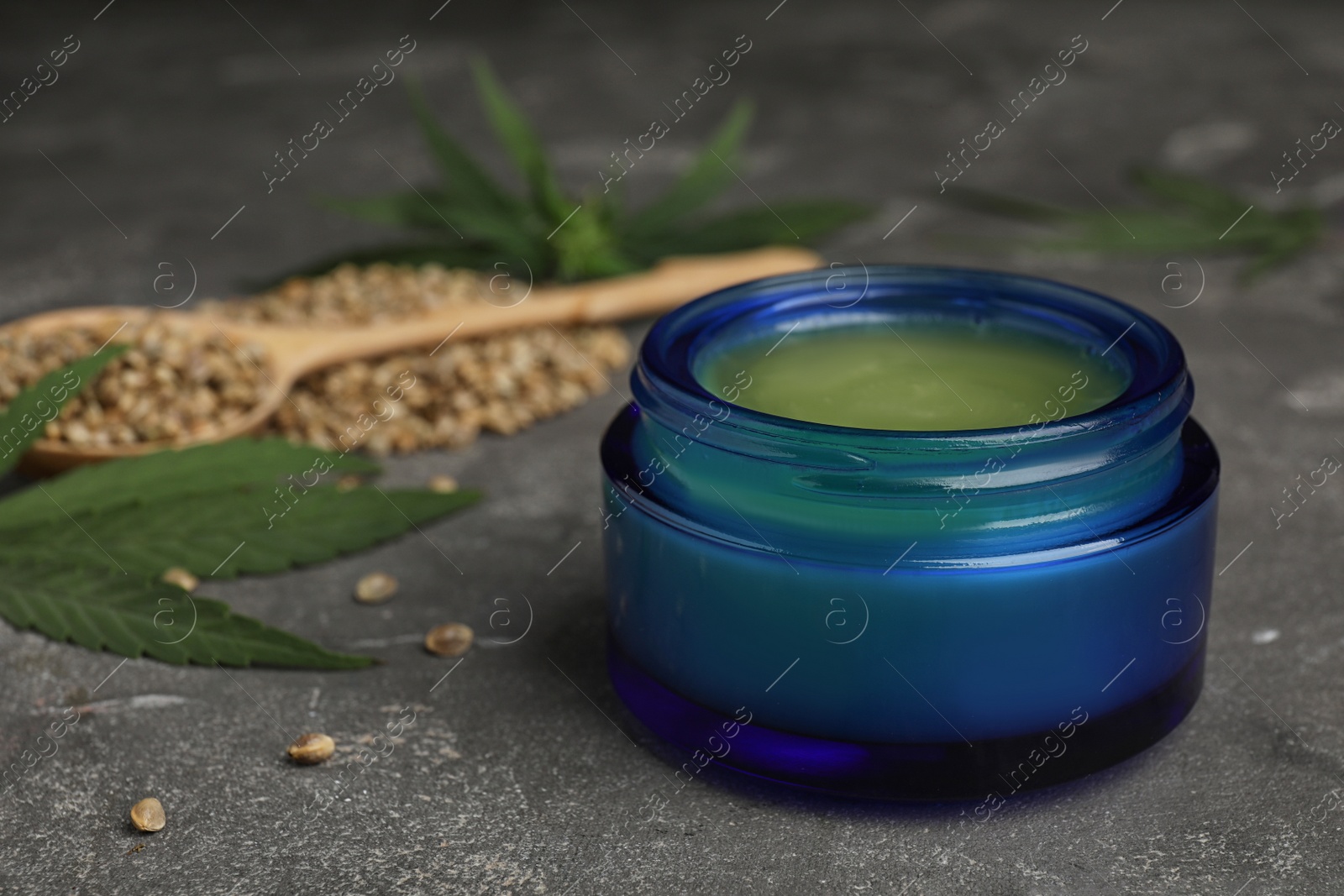 Photo of Jar of hemp cream on grey stone table, space for text. Organic cosmetics
