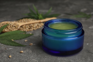 Photo of Jar of hemp cream on grey stone table, space for text. Organic cosmetics