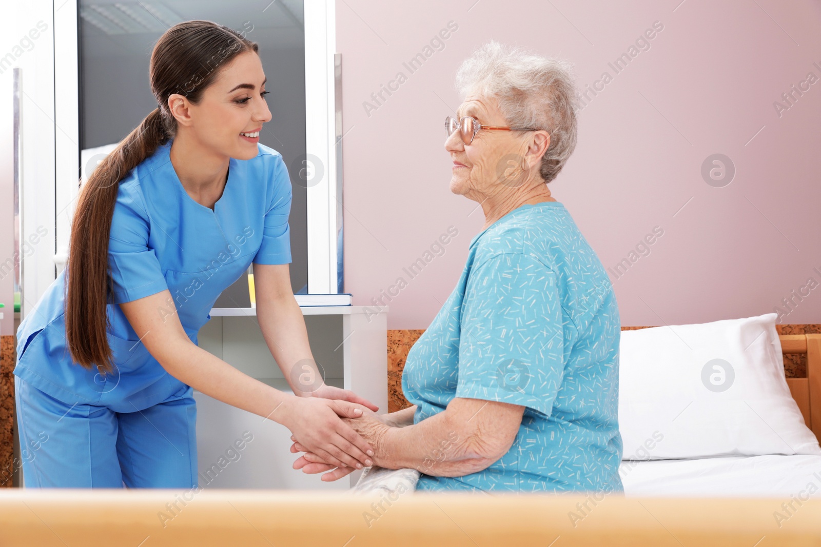 Photo of Nurse holding senior woman's hands in hospital ward. Medical assisting