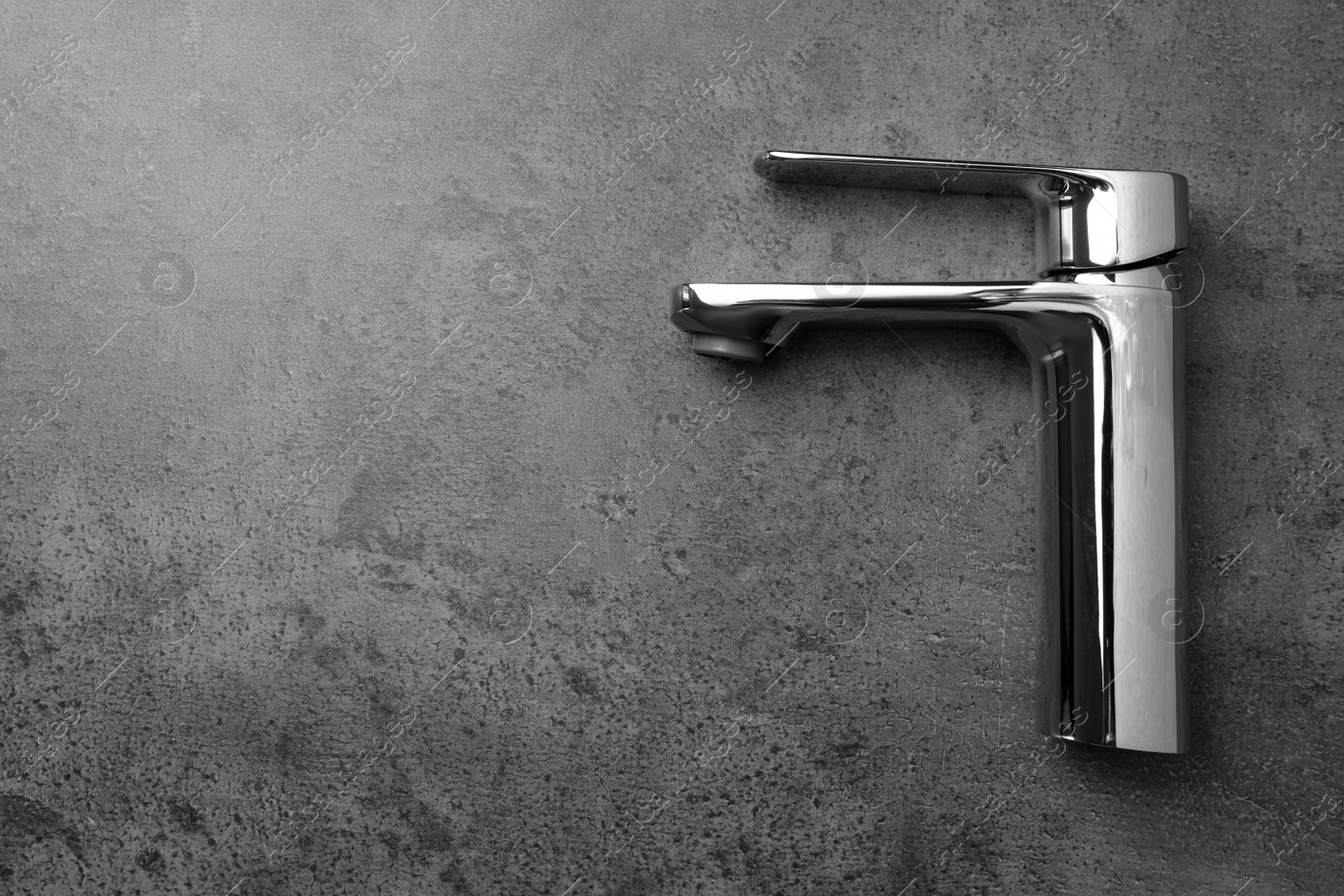 Photo of Single handle water tap on grey table, top view. Space for text