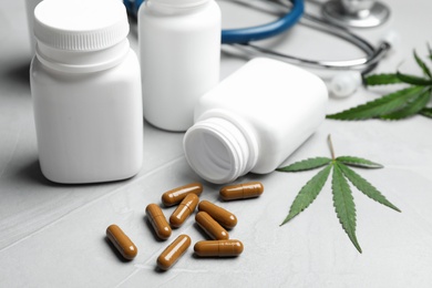Photo of Hemp leaf and bottles with capsules on grey table