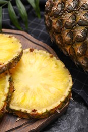 Photo of Slices of tasty ripe pineapple on black table, closeup
