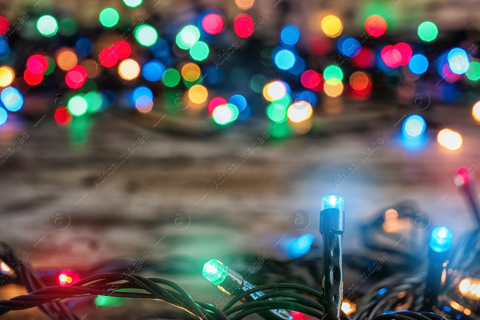 Photo of Beautiful bright Christmas lights on table, closeup