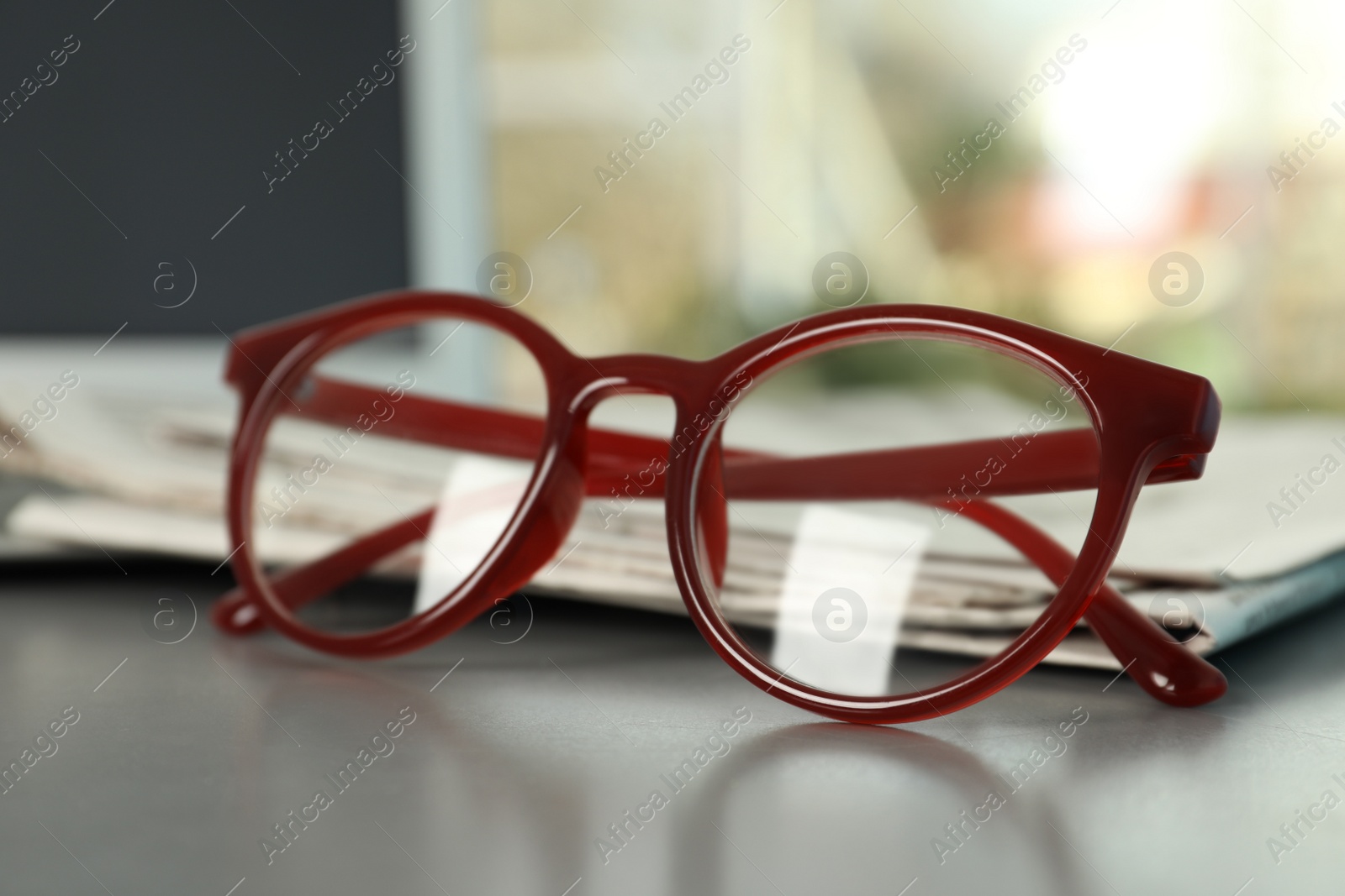 Photo of Newspapers and glasses on grey table indoors, closeup