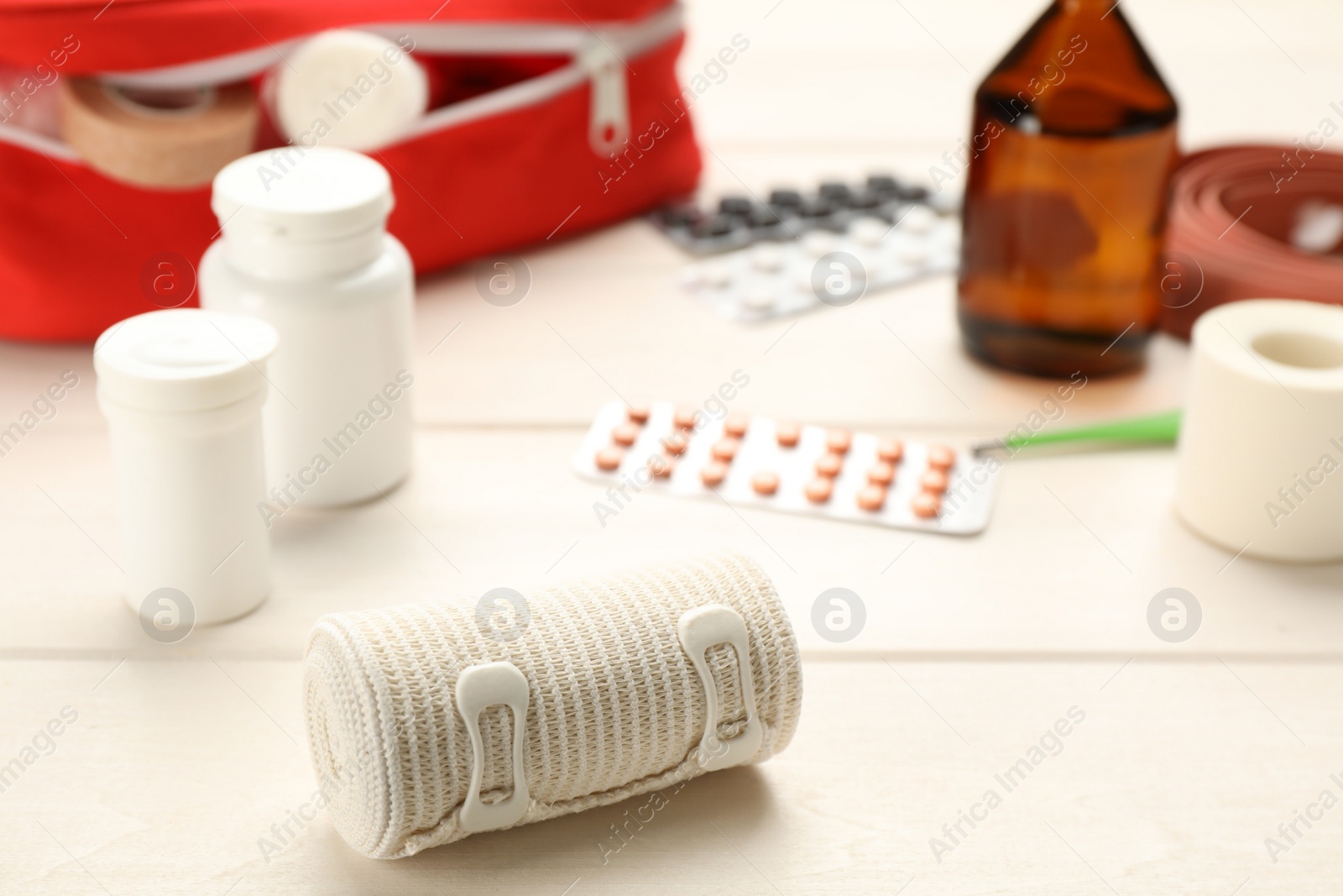Photo of Bandage and pills on white wooden table, closeup. First aid kit