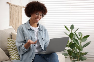 Young woman having video chat via laptop in room, space for text