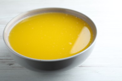 Photo of Clarified butter in bowl on white wooden table, closeup