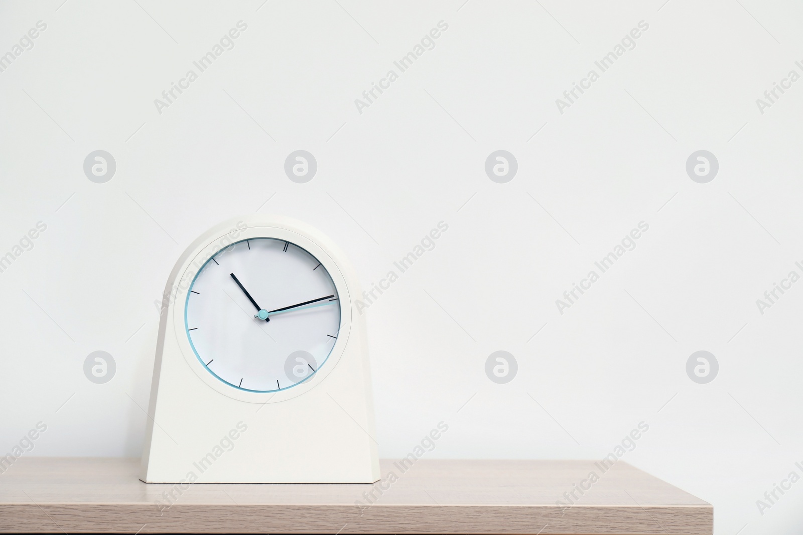 Photo of Modern clock on table against light background. Time concept