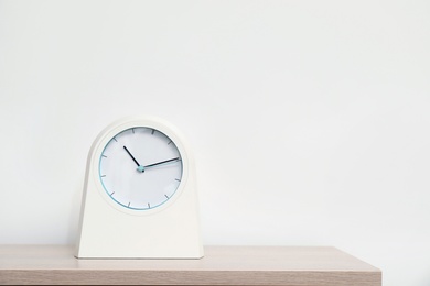 Photo of Modern clock on table against light background. Time concept