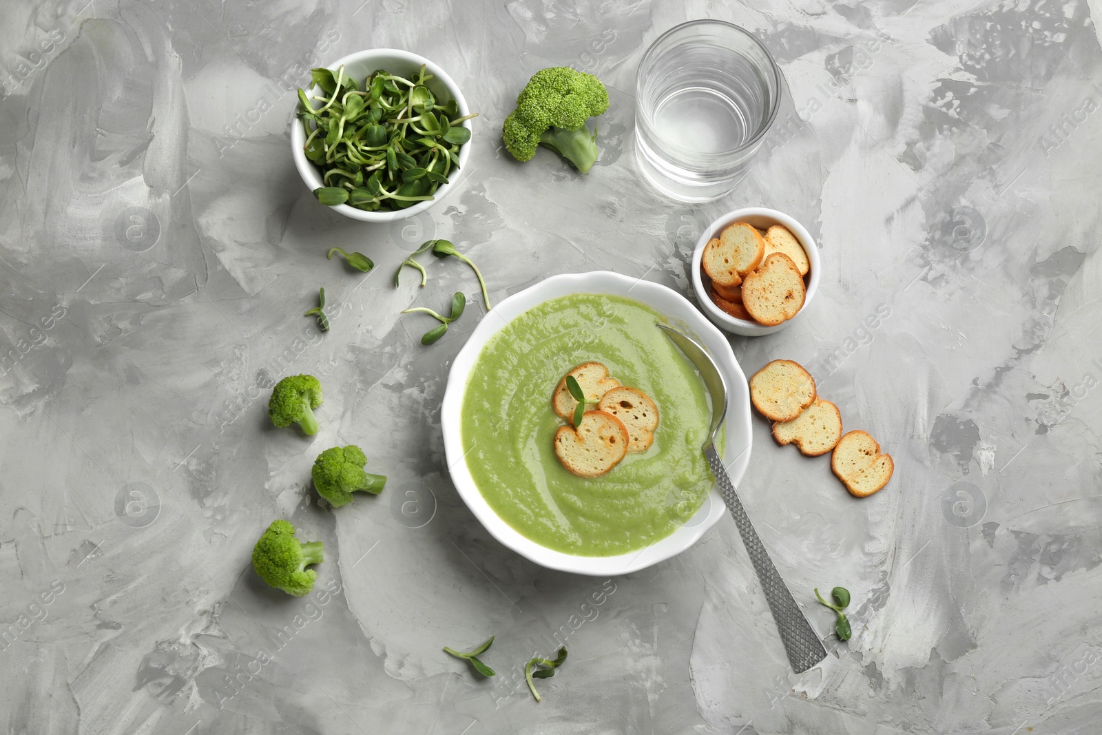 Photo of Flat lay composition with bowl of broccoli cream soup on grey table