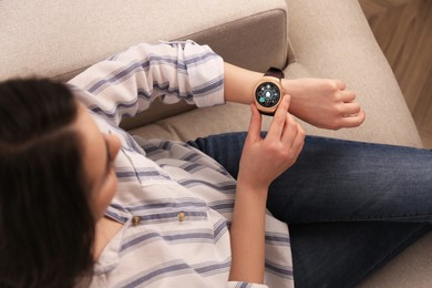 Image of Woman setting smart home control system via smartwatch indoors, above view. App interface with icons on display