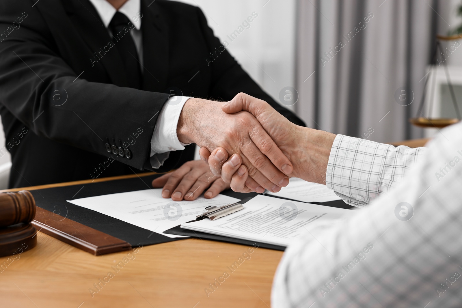 Photo of Lawyer shaking hands with client in office, closeup