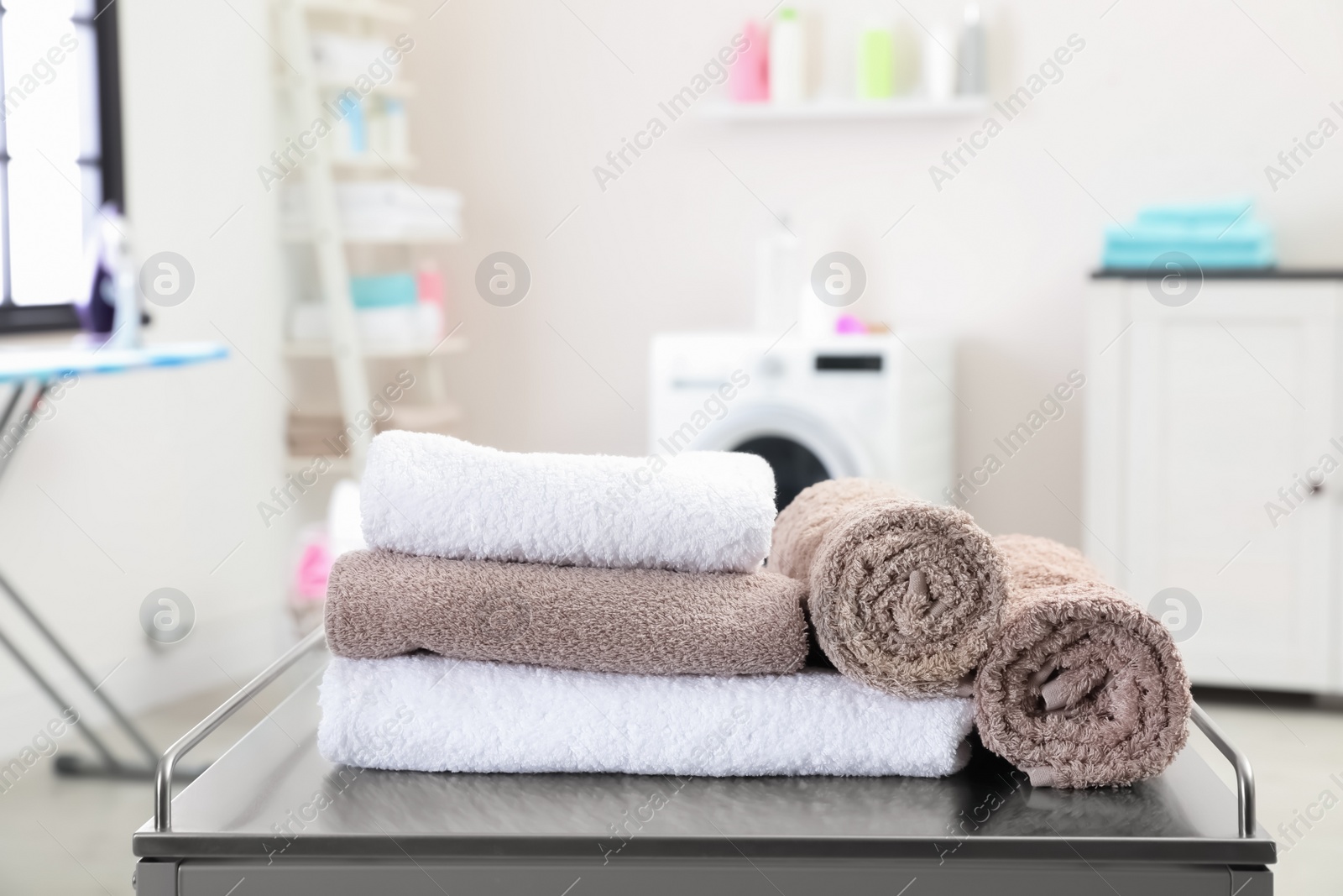 Photo of Soft bath towels on table against blurred background