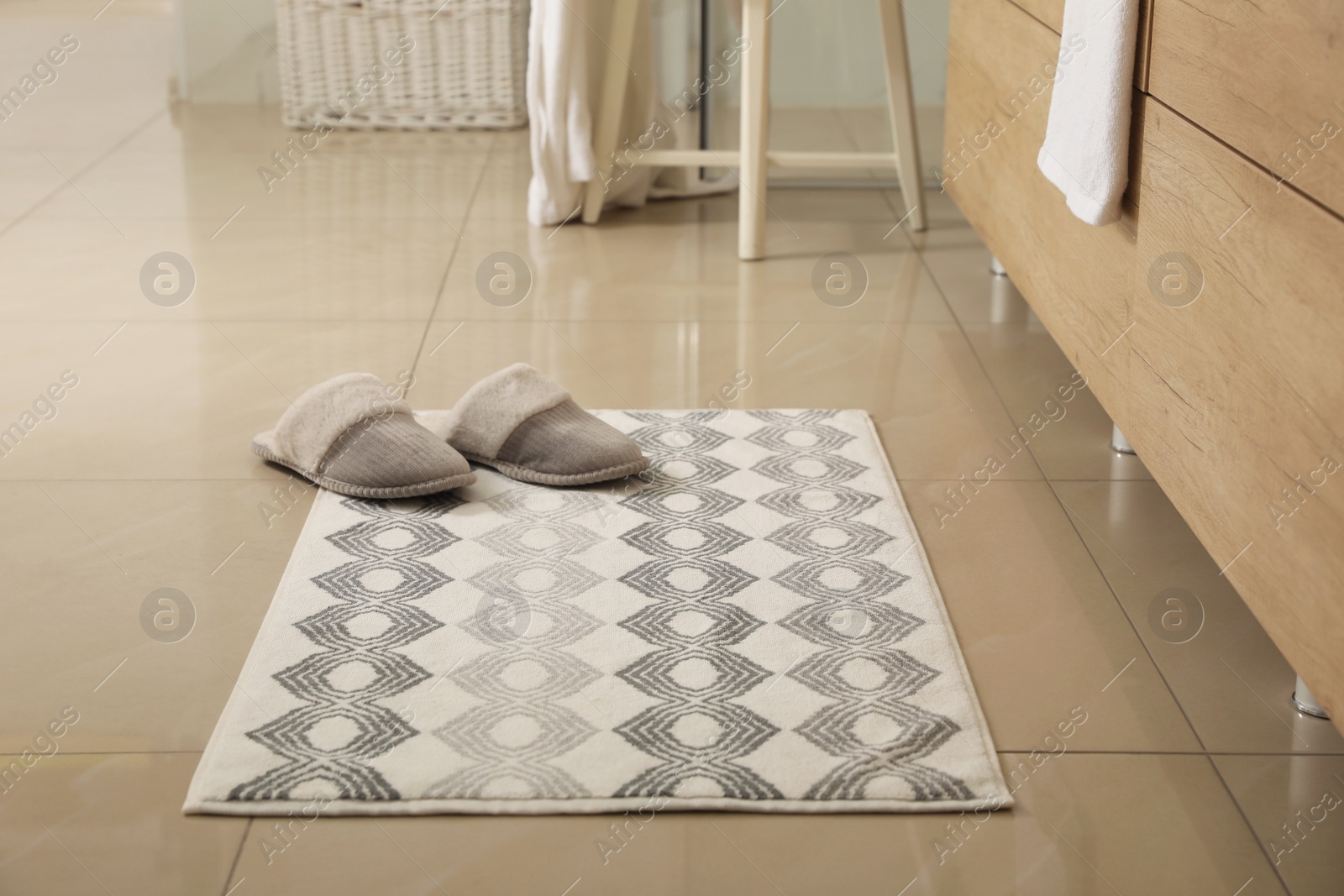 Photo of Soft bath mat and slippers on floor indoors