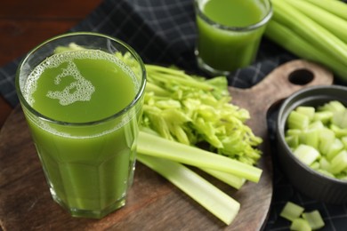 Photo of Glasses of delicious celery juice and vegetables on wooden board, closeup. Space for text