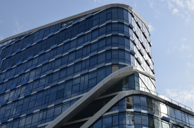 Exterior of beautiful modern skyscraper against blue sky, low angle view