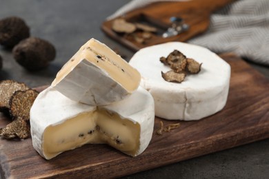 Photo of Wooden board with delicious truffle cheeses on grey table, closeup