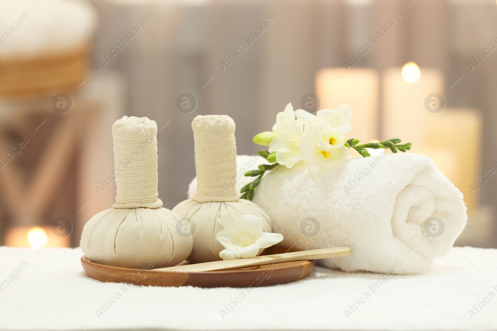 Photo of Beautiful composition with different spa products and flowers on white towel against blurred background