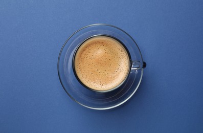 Photo of Fresh coffee in cup on blue background, top view