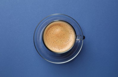 Fresh coffee in cup on blue background, top view