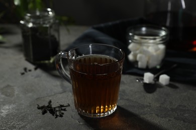 Photo of Tasty hot tea in cup on grey table, closeup