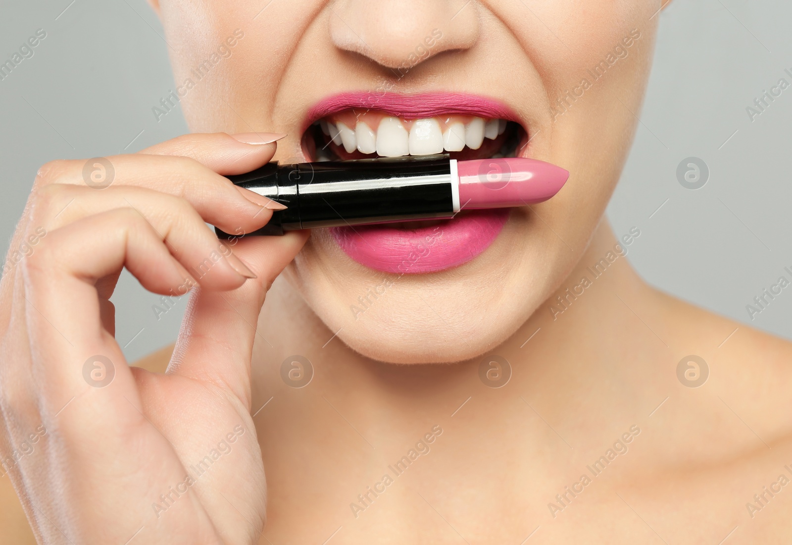 Photo of Young woman with beautiful lipstick on gray background, closeup