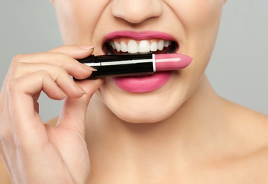 Young woman with beautiful lipstick on gray background, closeup