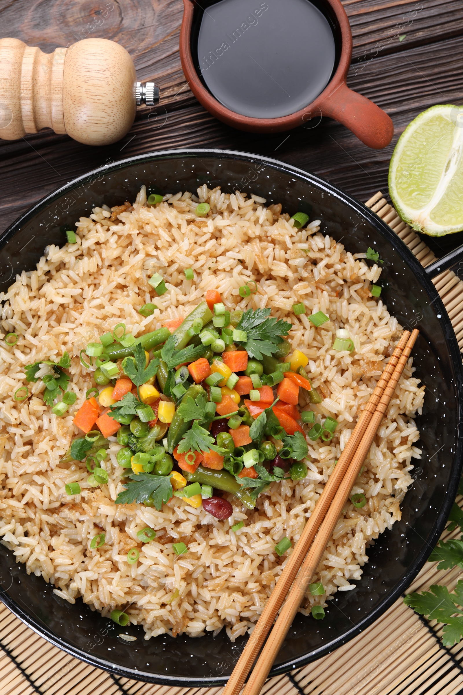 Photo of Tasty fried rice with vegetables served on wooden table, flat lay