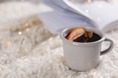 Photo of Beautiful composition with cup of mulled wine on white rug. Space for text