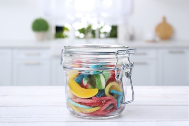 Image of Glass jar with tasty gummy candies on white wooden table in kitchen