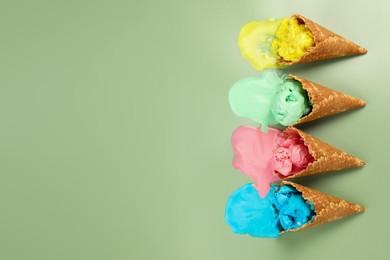 Photo of Melted ice cream in wafer cones on pale green background, flat lay. Space for text