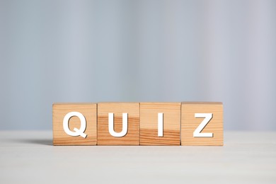 Photo of Wooden cubes with word Quiz on white table. Space for text