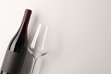 Bottle of tasty red wine and glass on white background, flat lay. Space for text