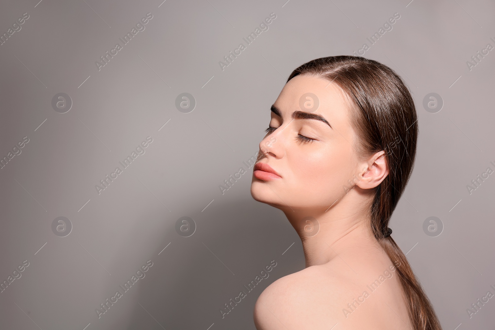 Photo of Beautiful woman with perfect eyebrows on gray background