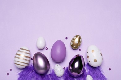 Photo of Flat lay composition with festively decorated Easter eggs on lilac background. Space for text