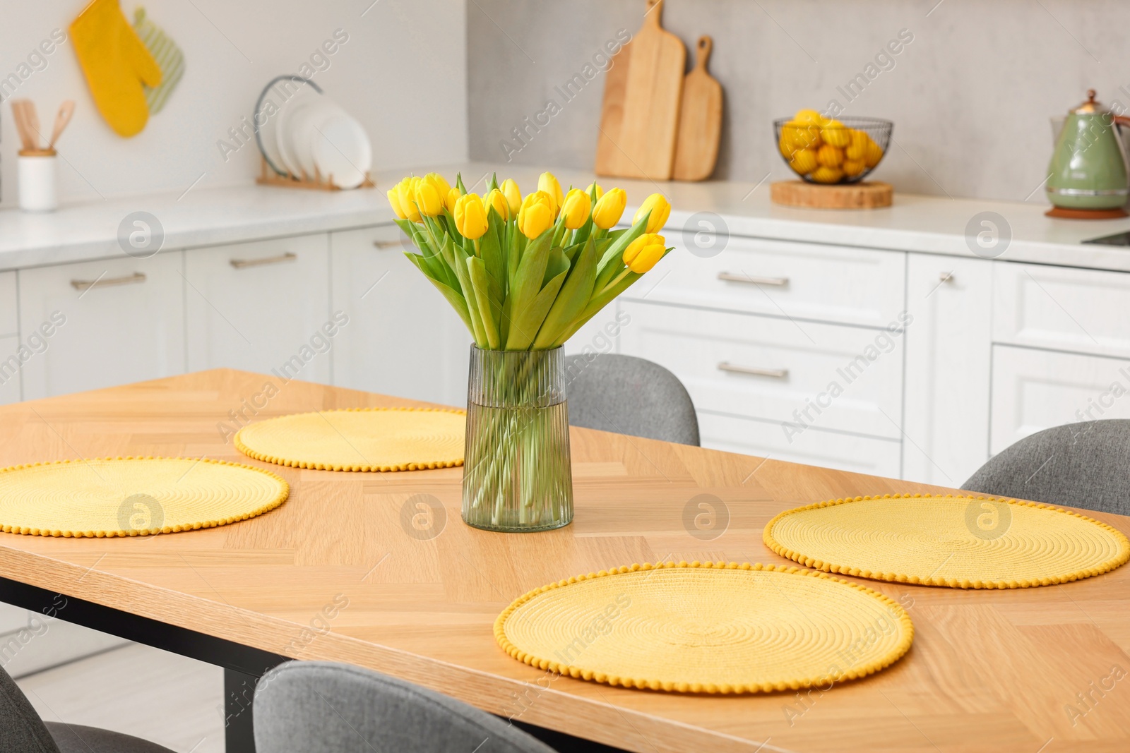 Photo of Spring interior. Bouquet of beautiful yellow tulips on wooden table in stylish kitchen